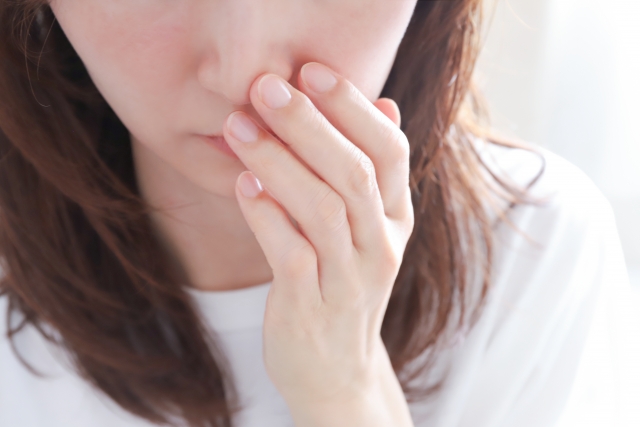 鼻を押さえる女性の目の下から胸辺りまでのアップ