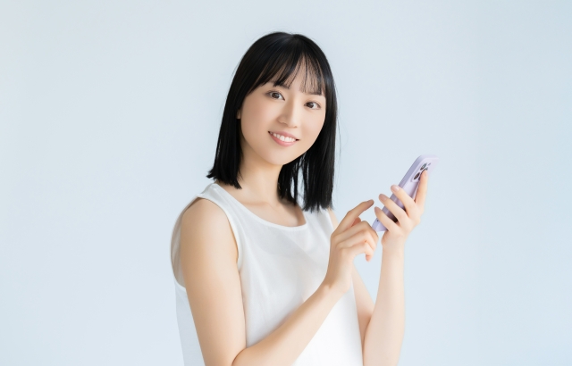 明るい表情でスマートフォンを持つ若い女性