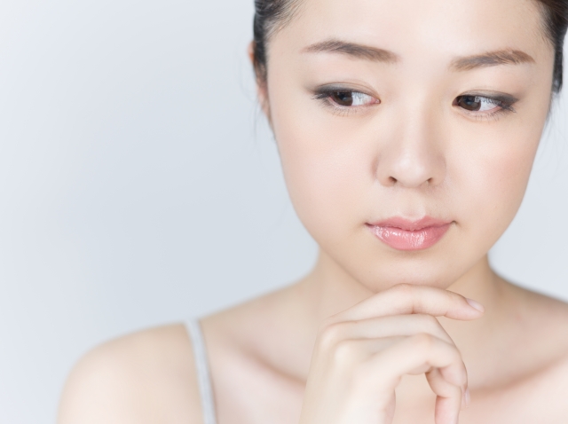 顎に手をあて考えている女性