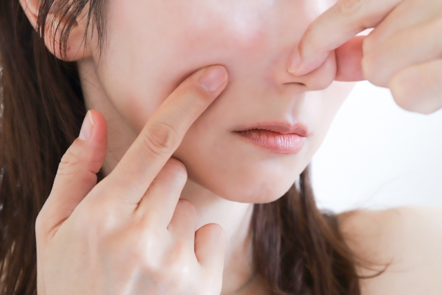 小鼻をつまんで悩んでいる女性