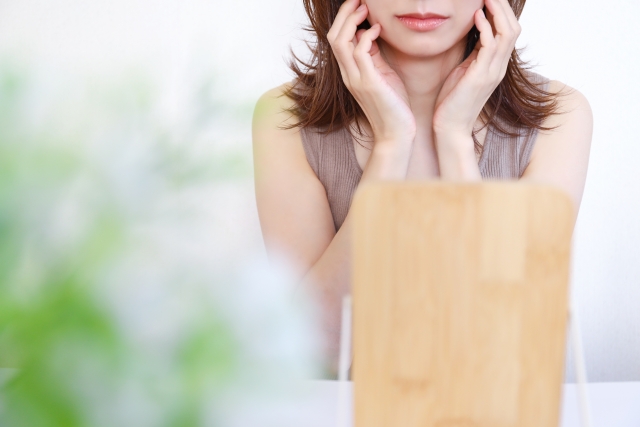 手を頬に添え鏡を見つめる女性