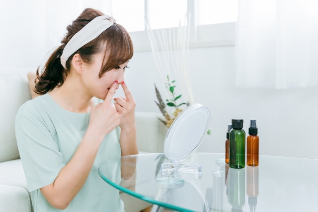 鏡を見ながら小鼻を触る女性