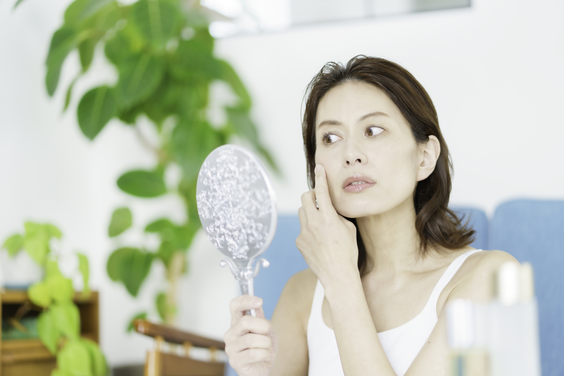 鏡を見ながら目元を気にする女性