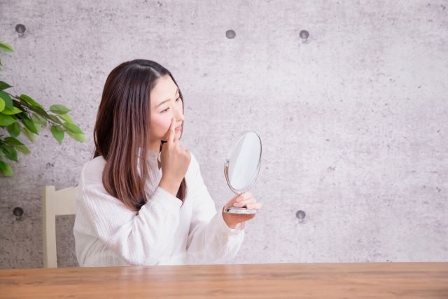 鏡を見ながら鼻を触る女性